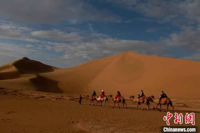 图为甘肃省敦煌市鸣沙山月牙泉景区内，游客沐浴着晨光，欣赏大漠风光，仿佛置身画卷当中。　张晓亮 摄